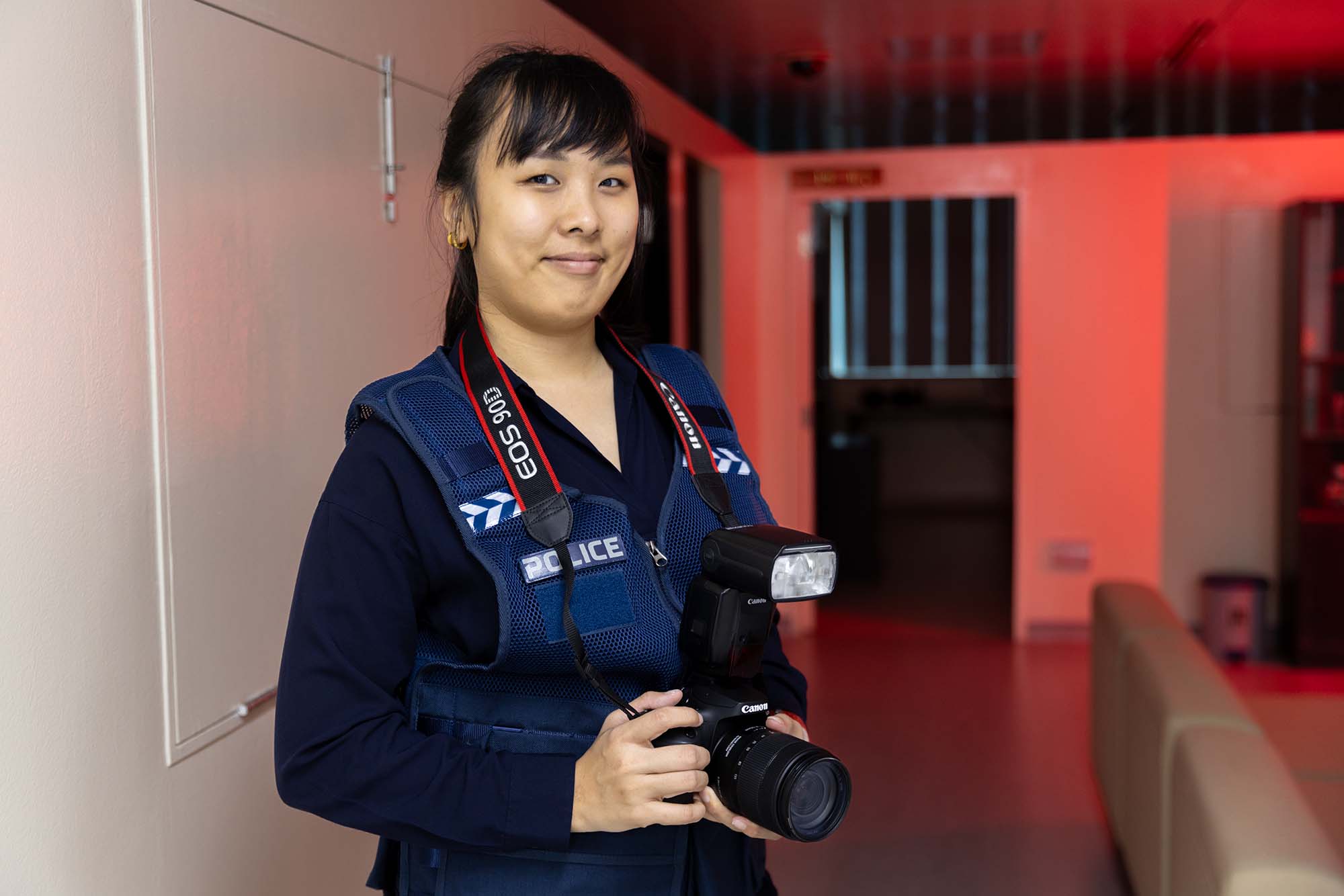 Ms Chiam Hui Ting holds a camera and poses at her workplace. 