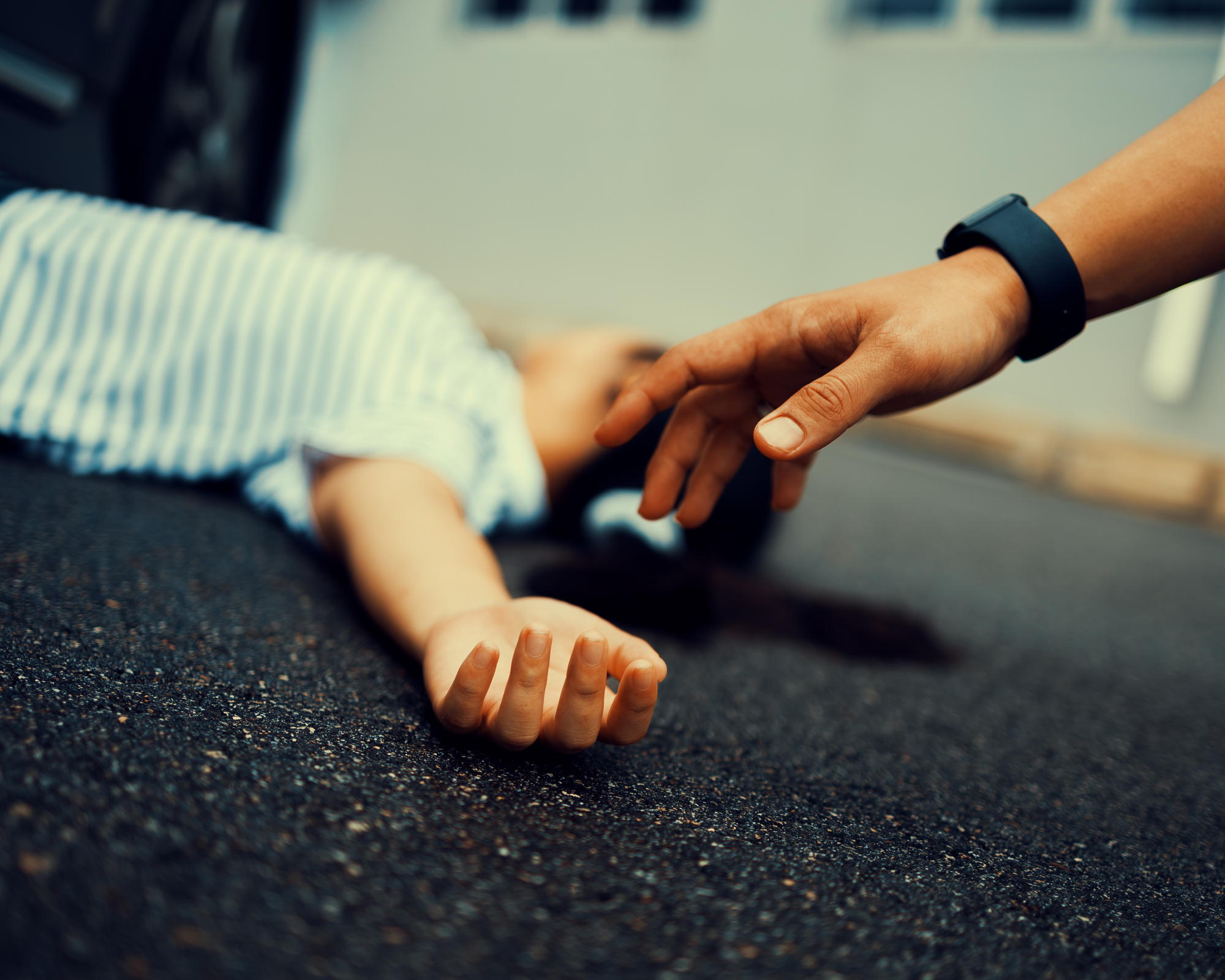 a photo of a teaser image showing a lady lying on the road under a car and a man reaching out to her
