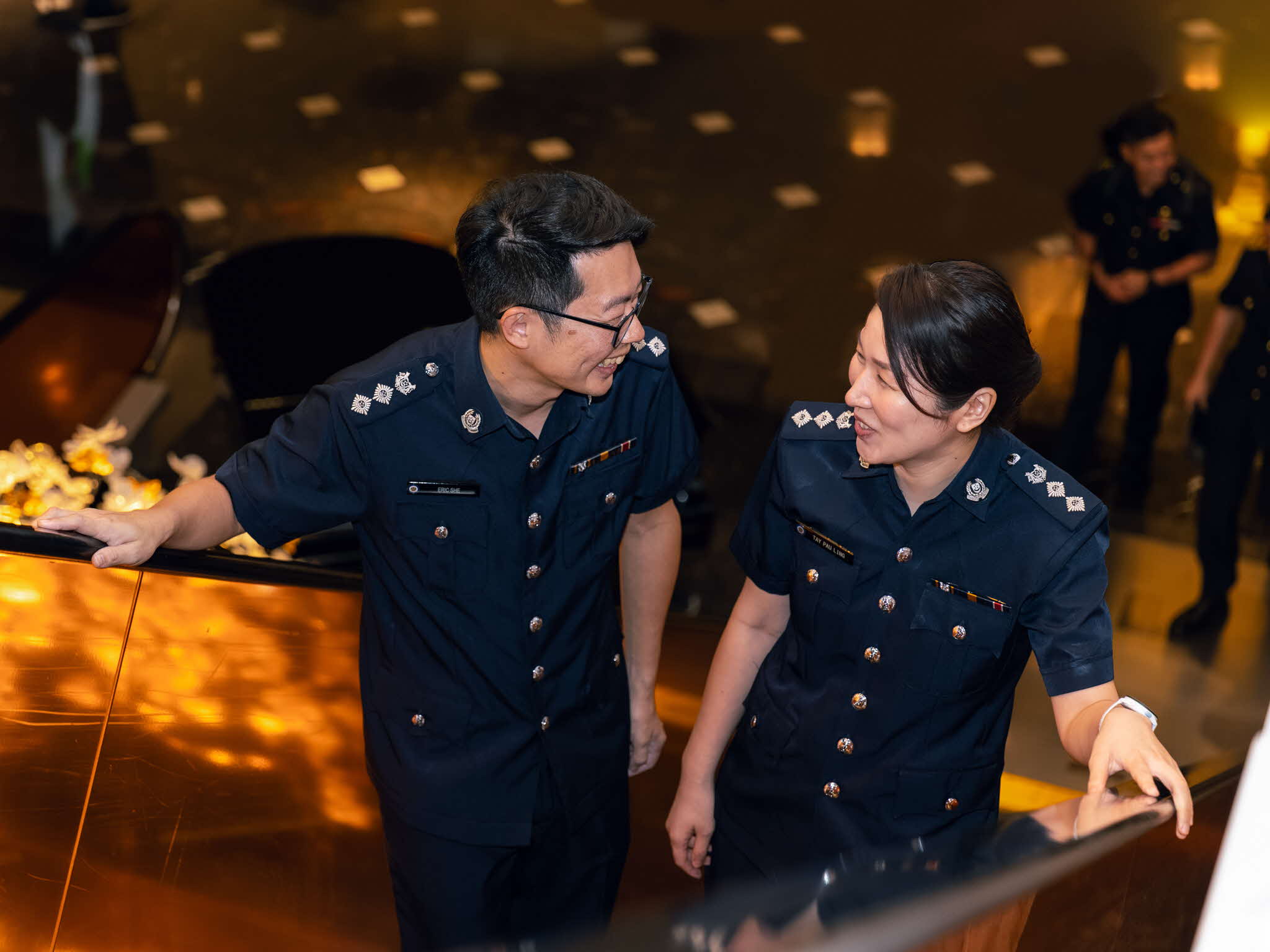 Supt She Zhao Zuo and Supt Tay Pau Ling looking at each other at escalator.