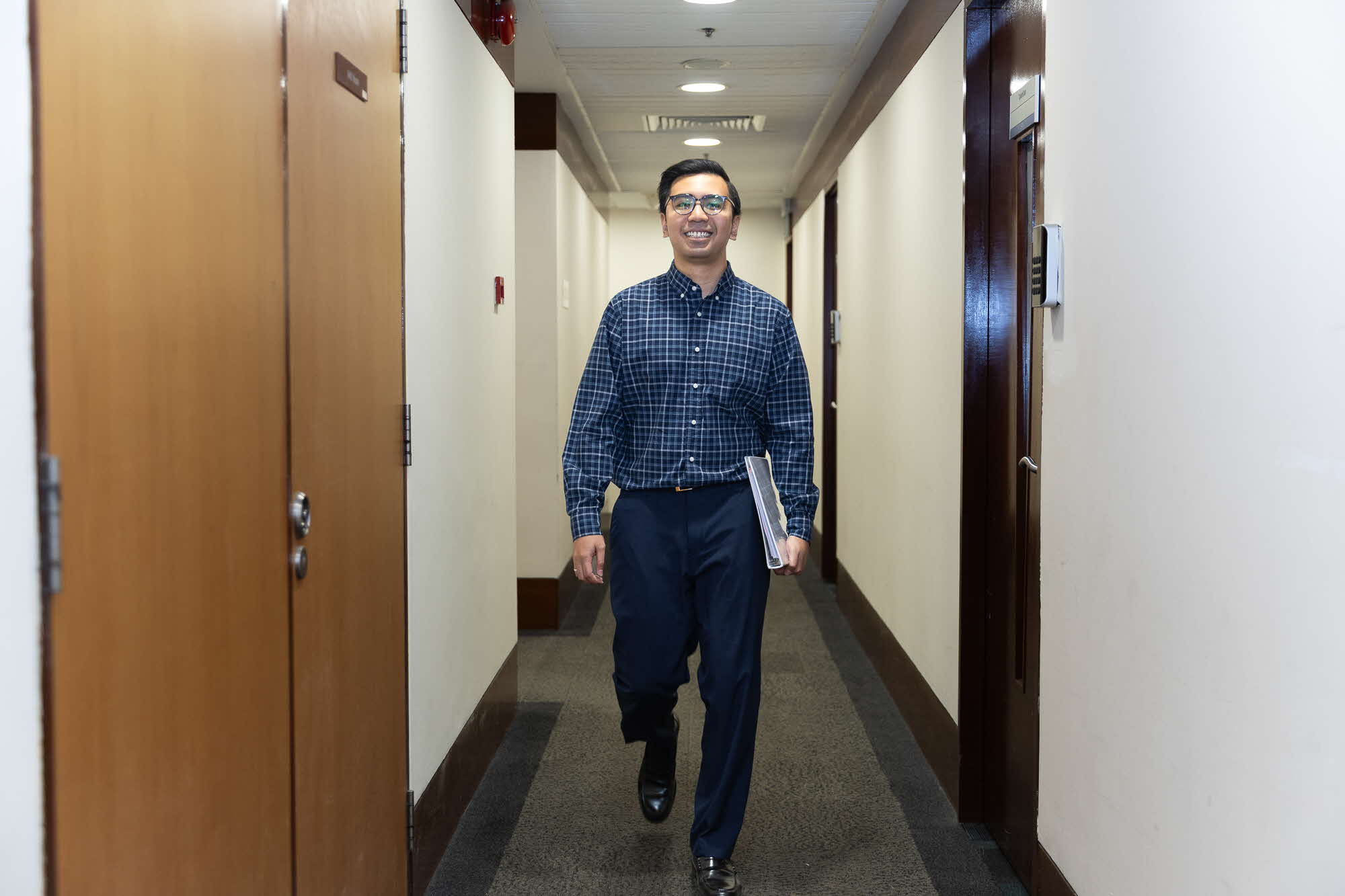 Mr Muhammad Syazwan walking along his office corridor.