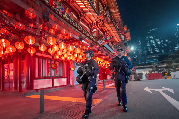 ERT officers patrolling beside buddha tooth relic temple, with red shiny lanterns in background