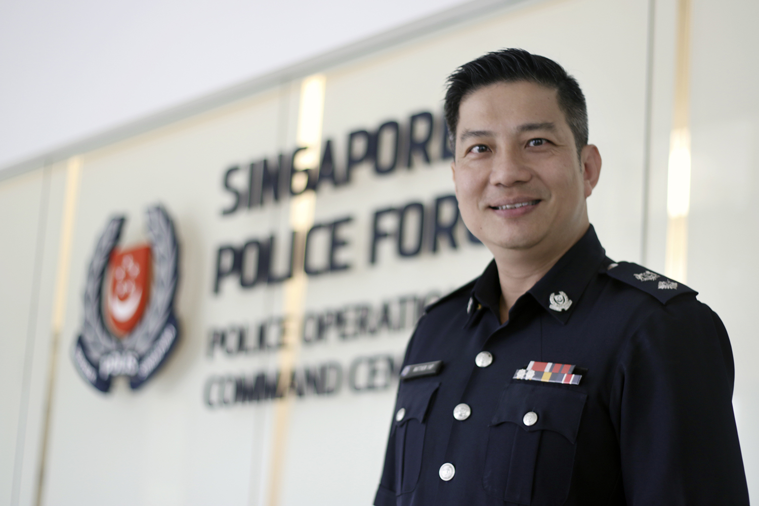 A police officer in uniform standing infront of the Police operations Command Centre building entrance