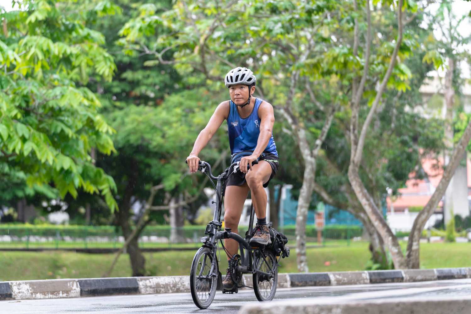 SI Lim cycling along a path in a park wearing a cycling helmet.