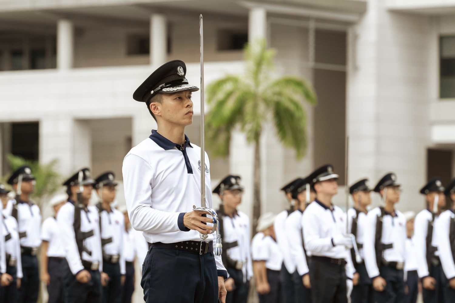 photo of DAC Tan infront of the contingent, in a stationary position with his sword pointing upwards, during a rehearsal