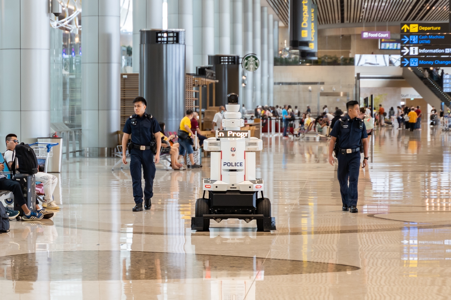 The SPF patrol robot in action at Changi Airport Terminal 4 with 2 police officers accompanying it on each side.