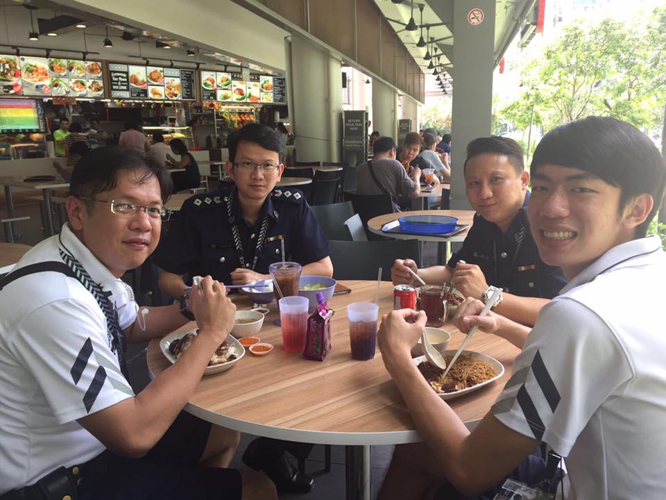 police officers sitting at a coffeeshop table in their police uniform, turning back and smiling for the camera