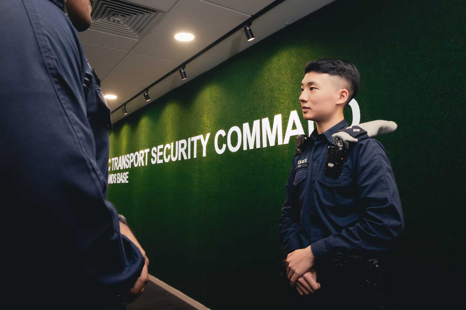 officer giving a briefing to a squad to the left, with a green background and white words stating "public transport security command"