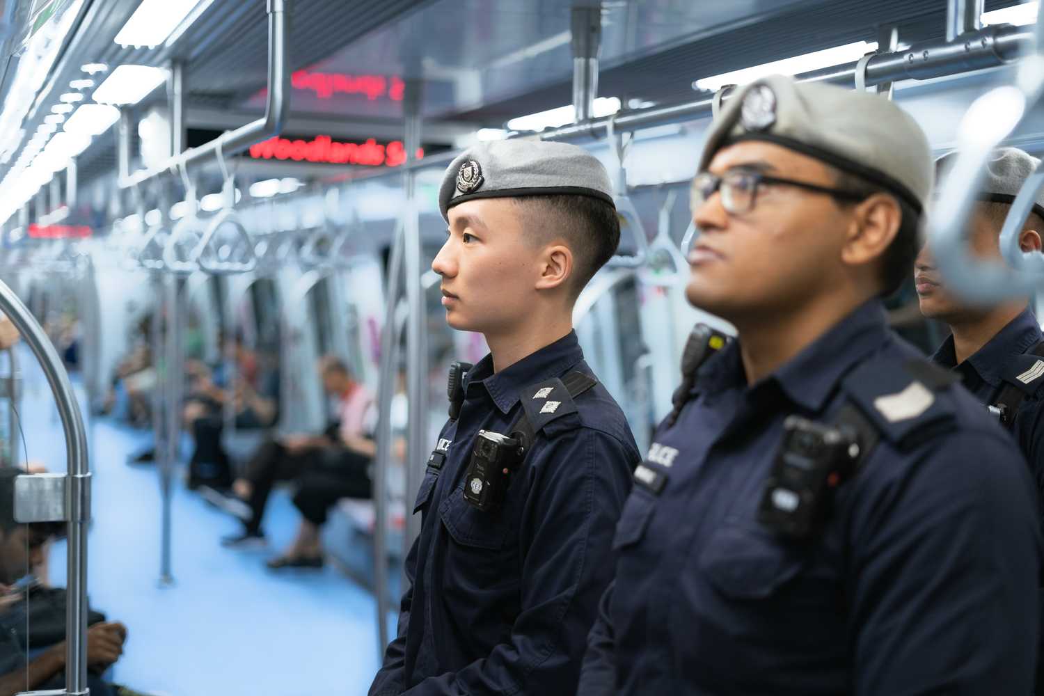 officers standing focused and facing the left, inside a moving train