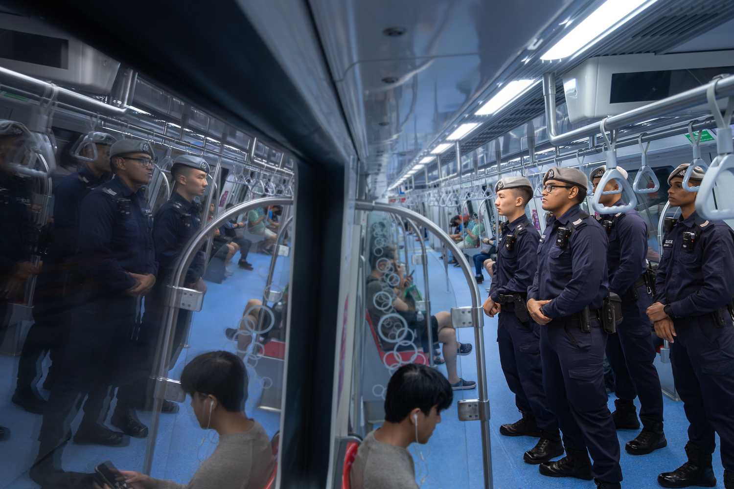 officers facing the left and can be seen in the reflection of the moving train's window