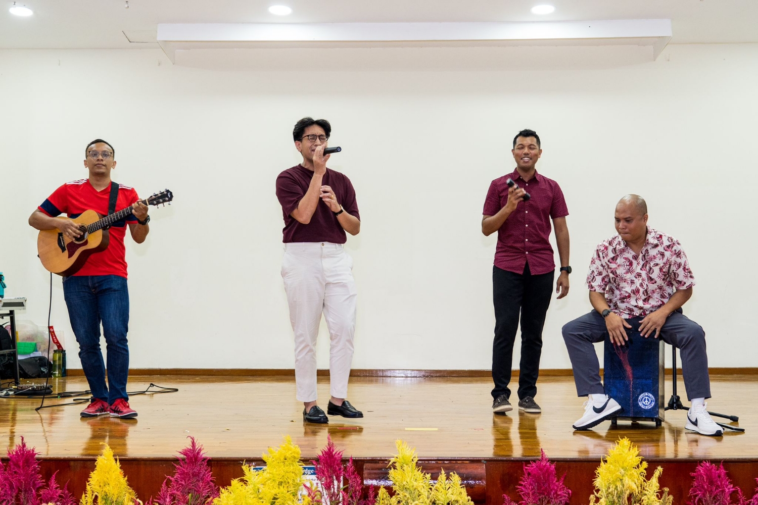 four people on stage performing music and singing 