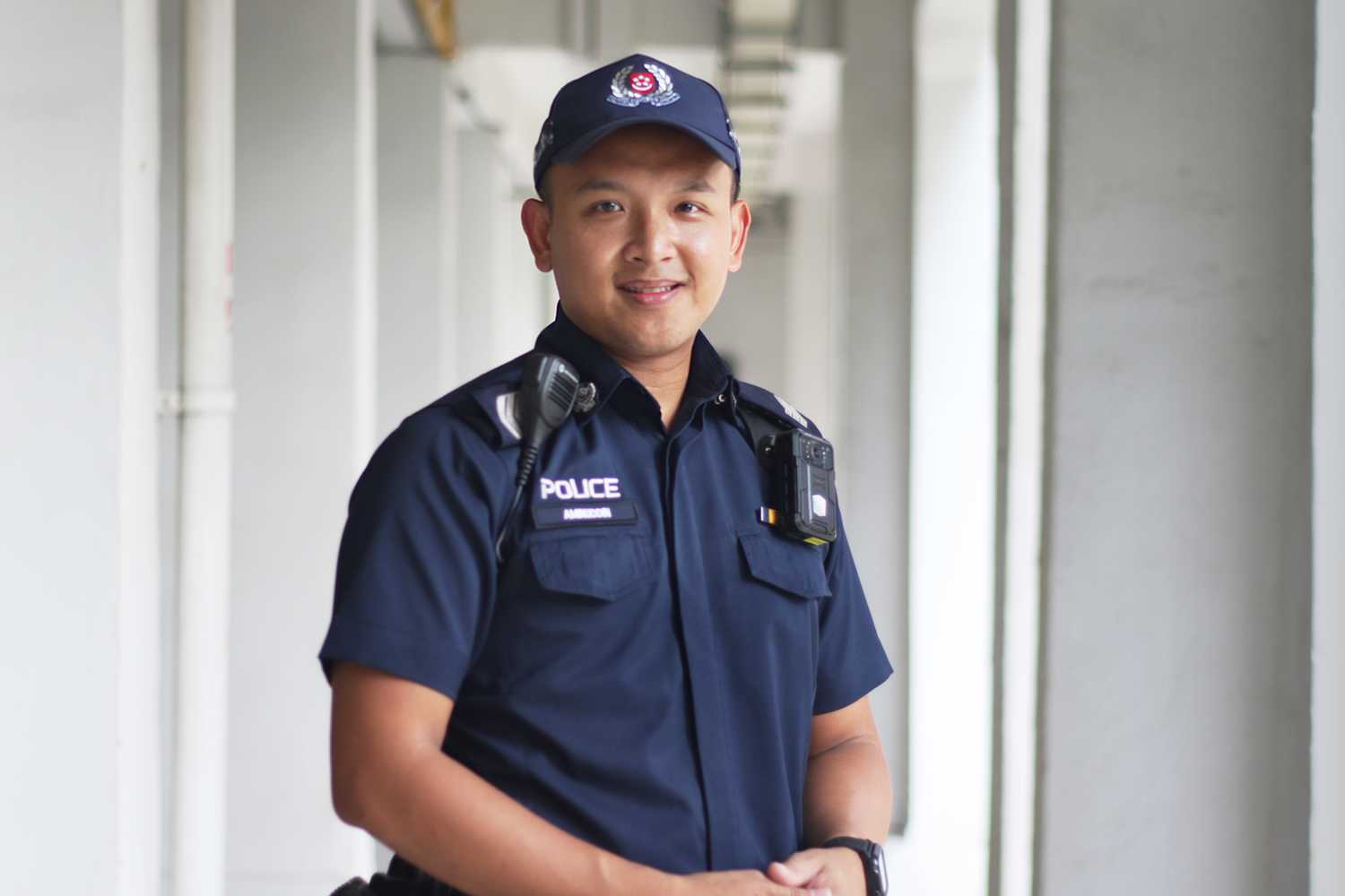 officer in blue uniform, standing facing the camera with the voiddeck's walkway behind him. 