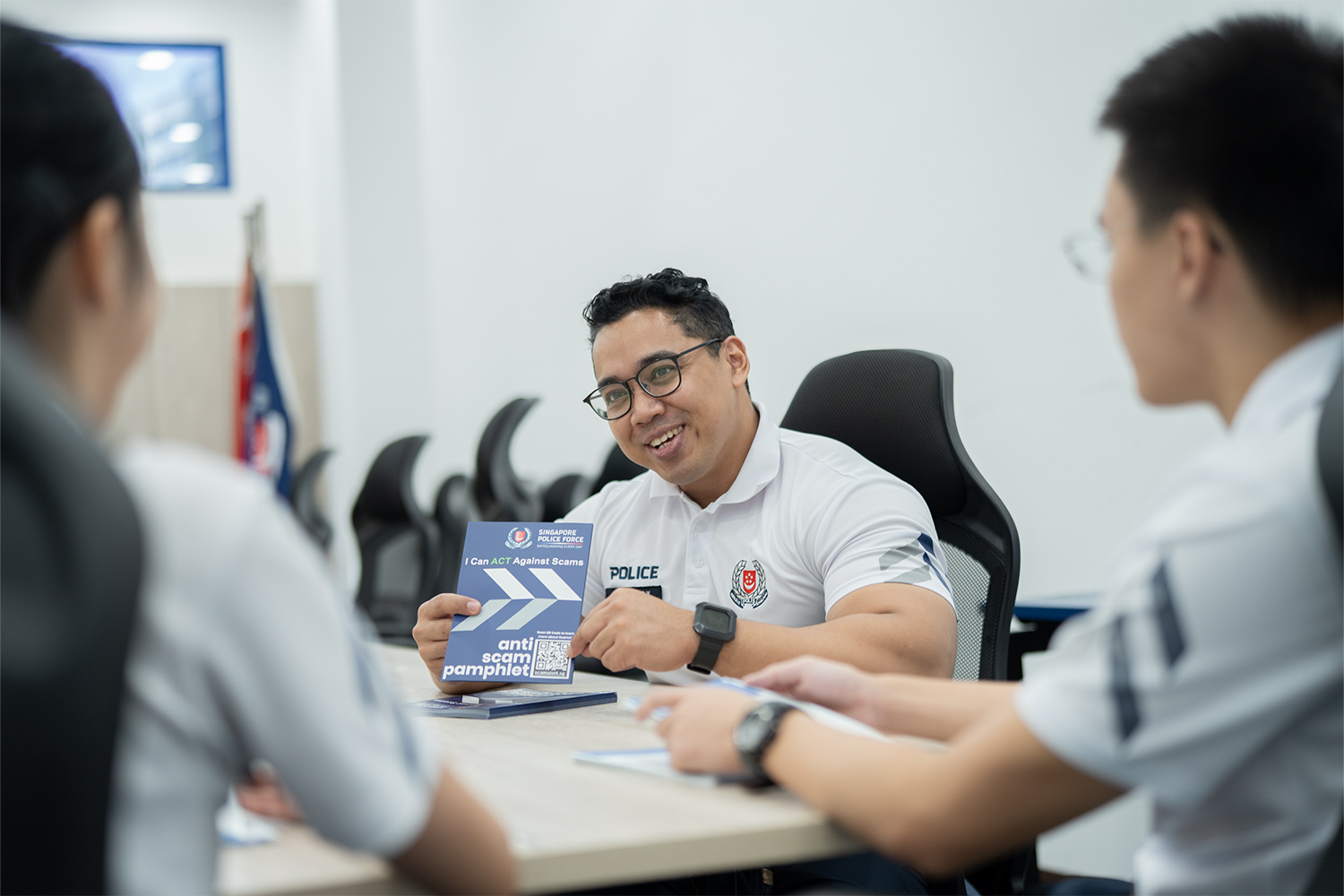 cpu officer in a briefing room sharing during a meeting and holding up a pamphlet 