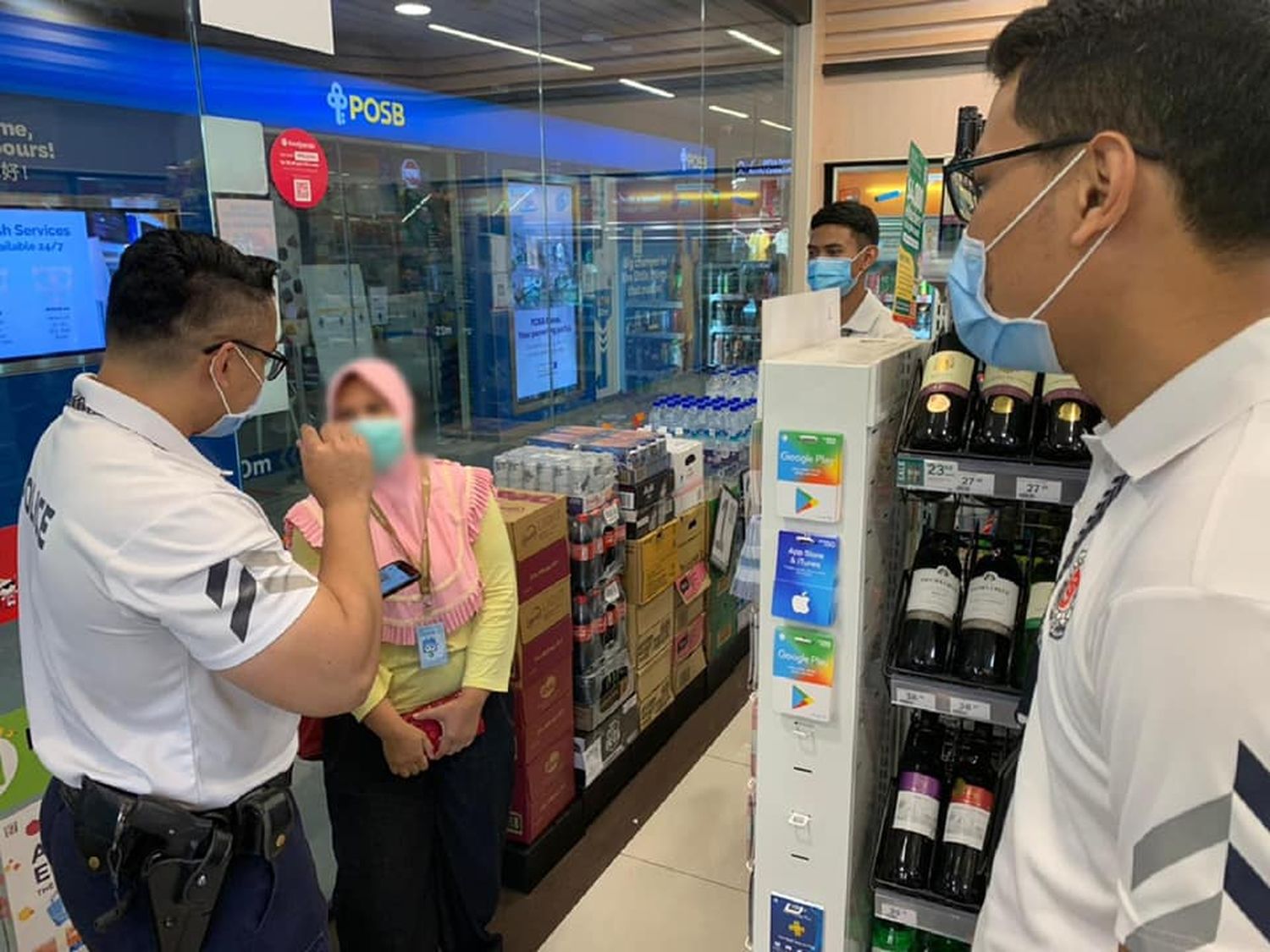 three CPU officers speaking to a lady whose face is blurred in a convenience store