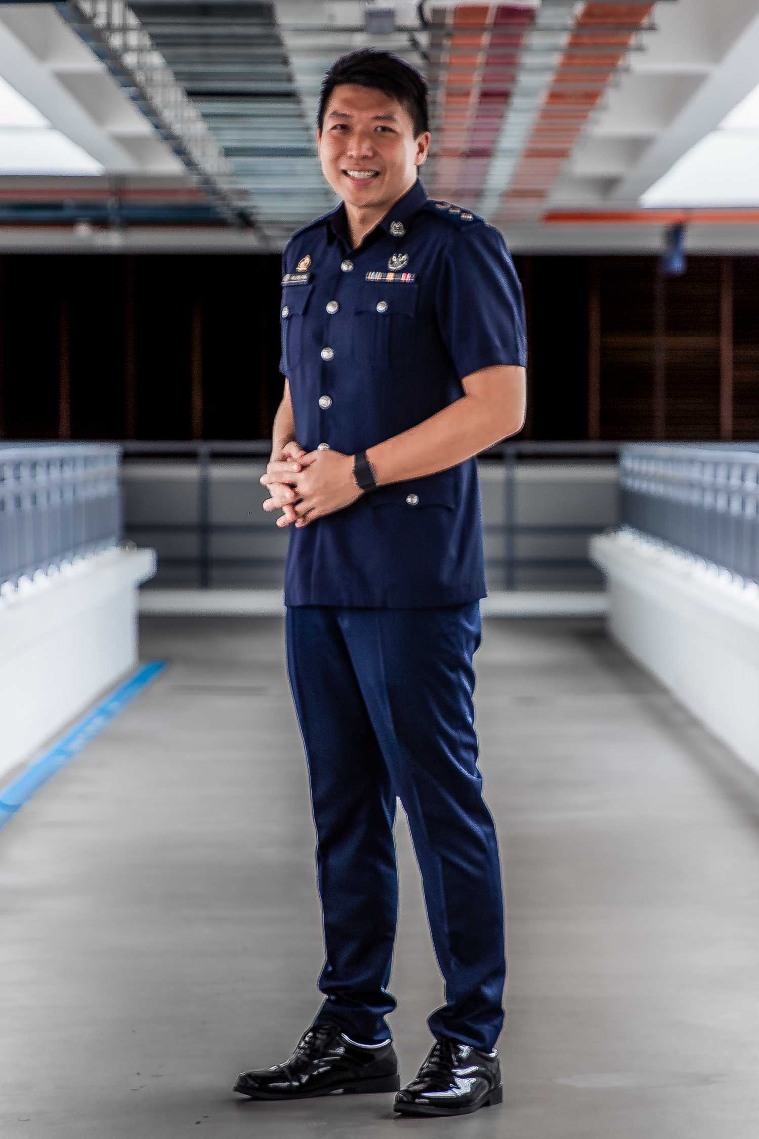 A profile shot of Superintendent of Police Koh Chao Rong in uniform, smiling and standing in front of the camera.