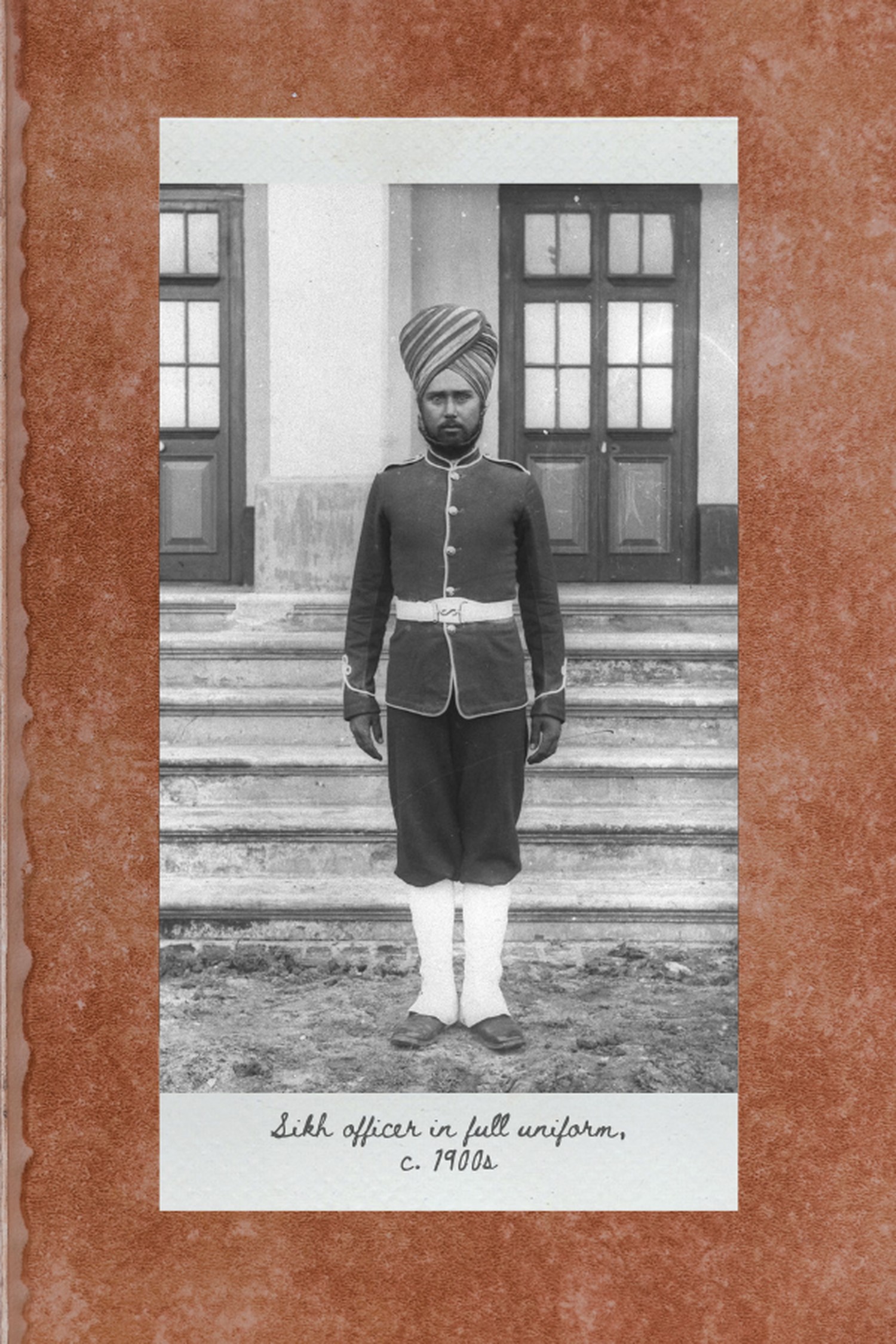an old black and white photo of a sikh officer wearing a full uniform with belt, high white socks and a turban