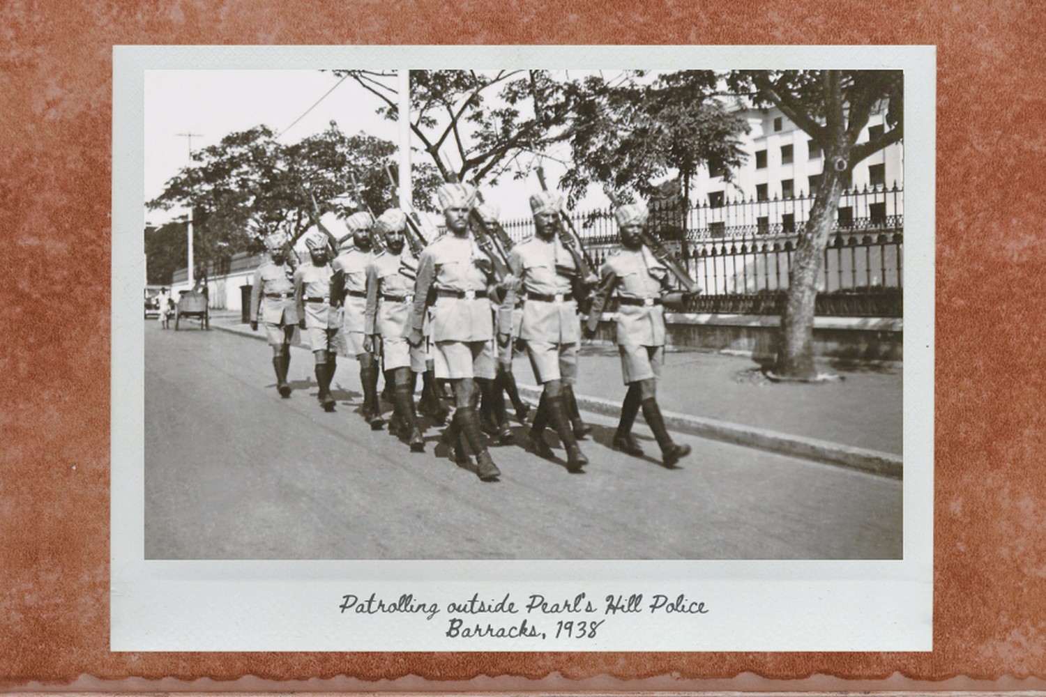 an old black and white photo of a sikh officers patrolling in a group, marching towards the right on a public road
