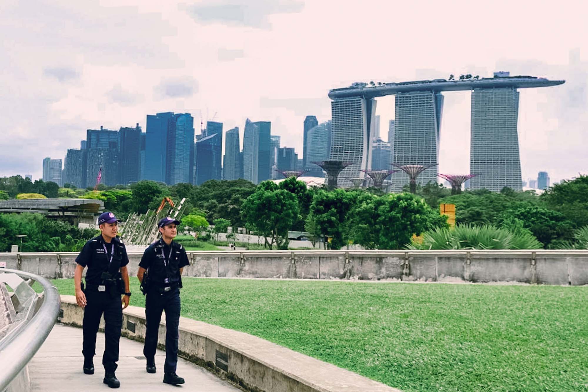 two officers patrolling and walking along a garden with the Marina Bay Sands building in the background
