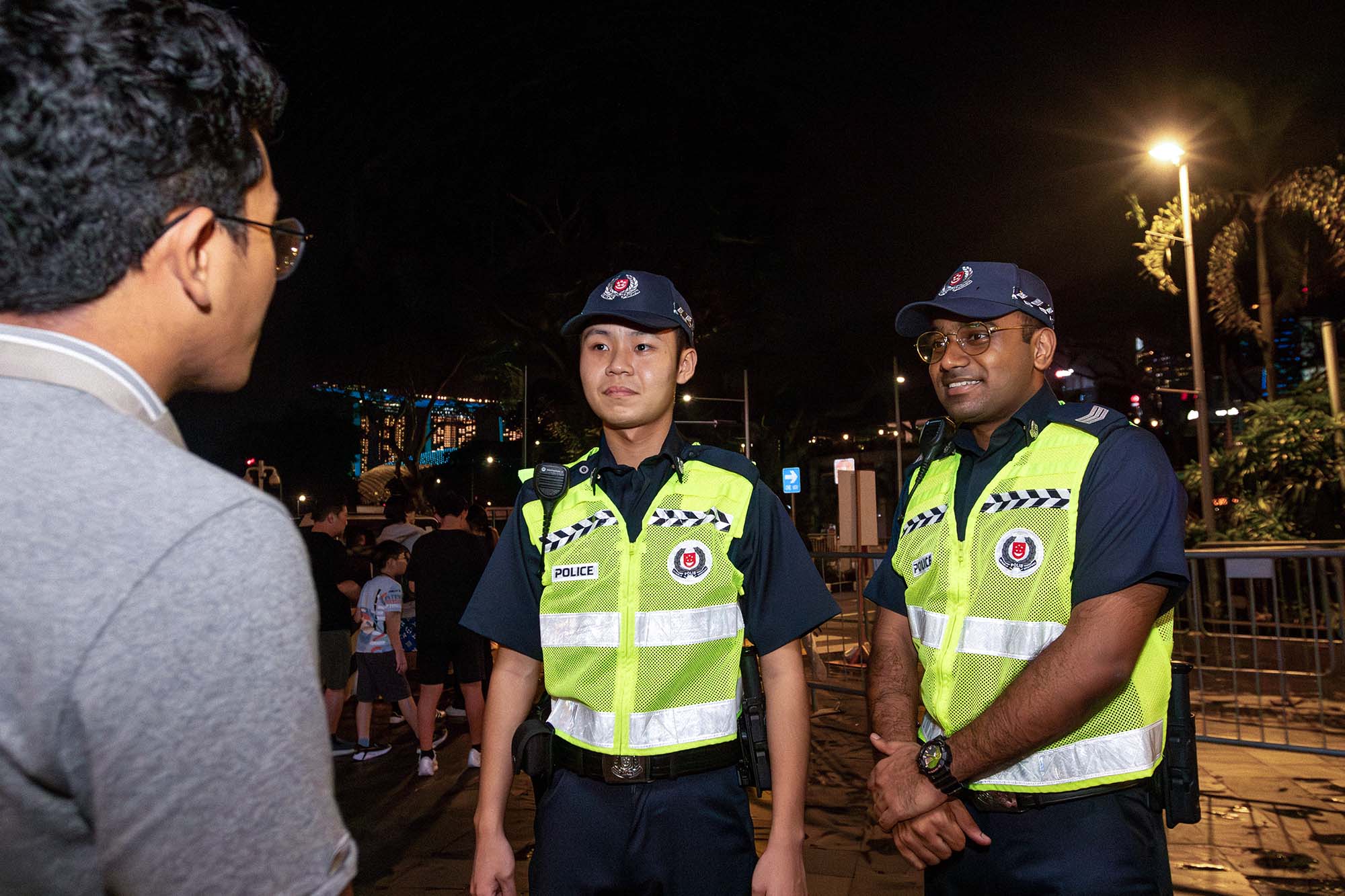 officers patrolling along the road with green vests at night, stopping and talking to a member of the public
