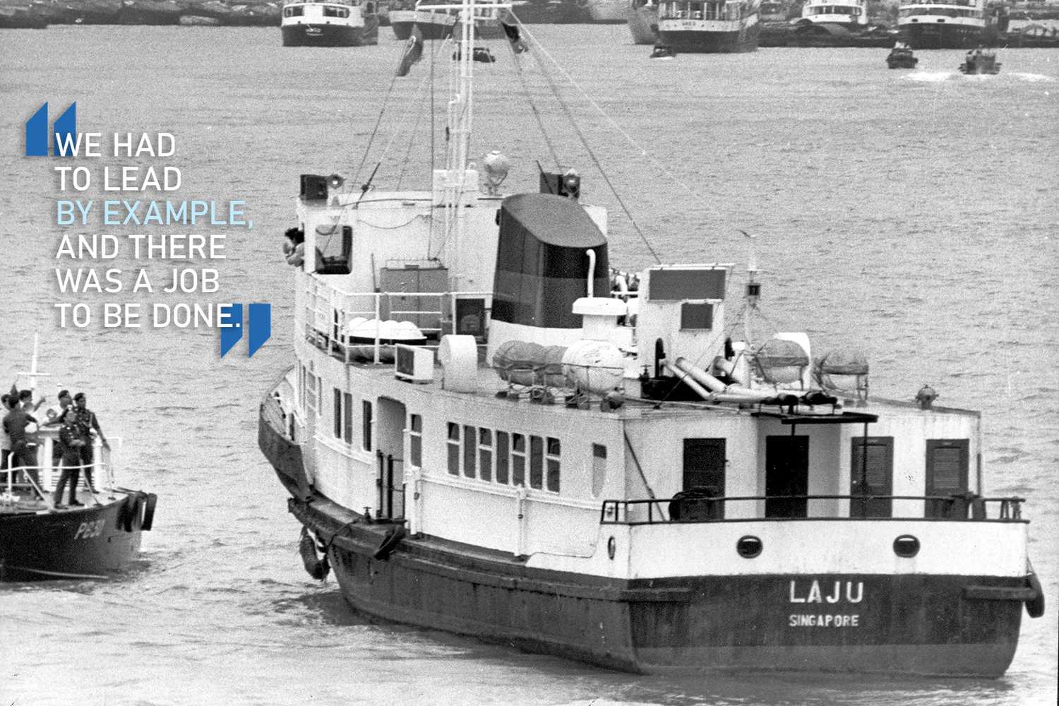 photo of the laju boat being surrounded by a police boat with a man standing on it and talking to the person on board the laju