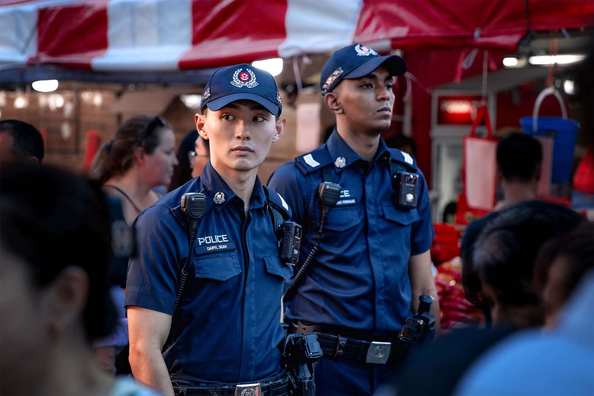 two male police officers walking amidst a crowd, looking around