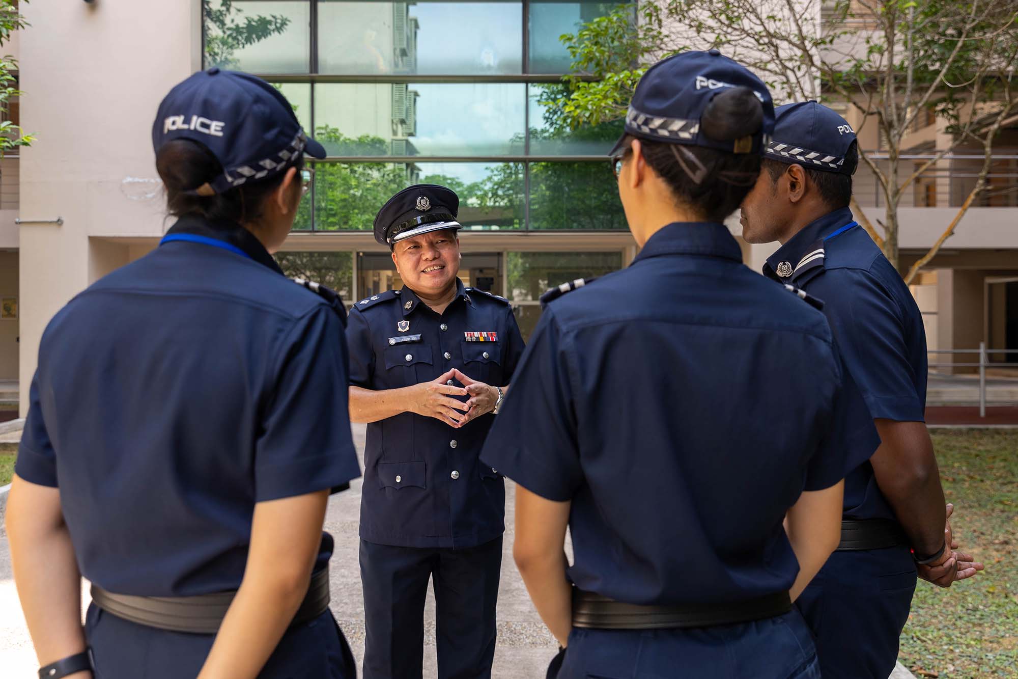 four officers standing together where one in the middle is talking to them. All are wearing the police uniform