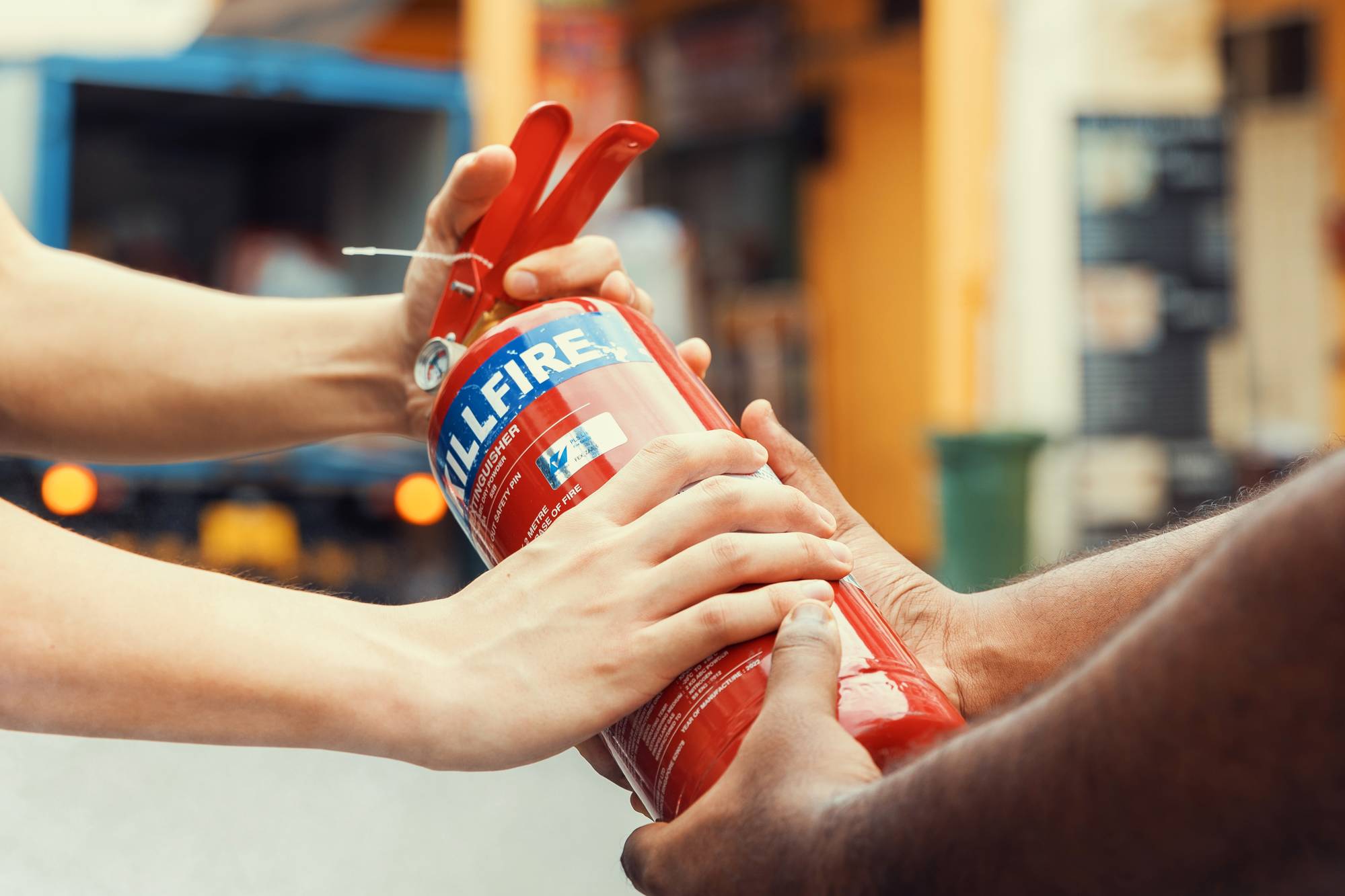 a shot of an officer receiving a fire extinguisher from a member of the public. The shot is only focused on their arms, handing over and taking 