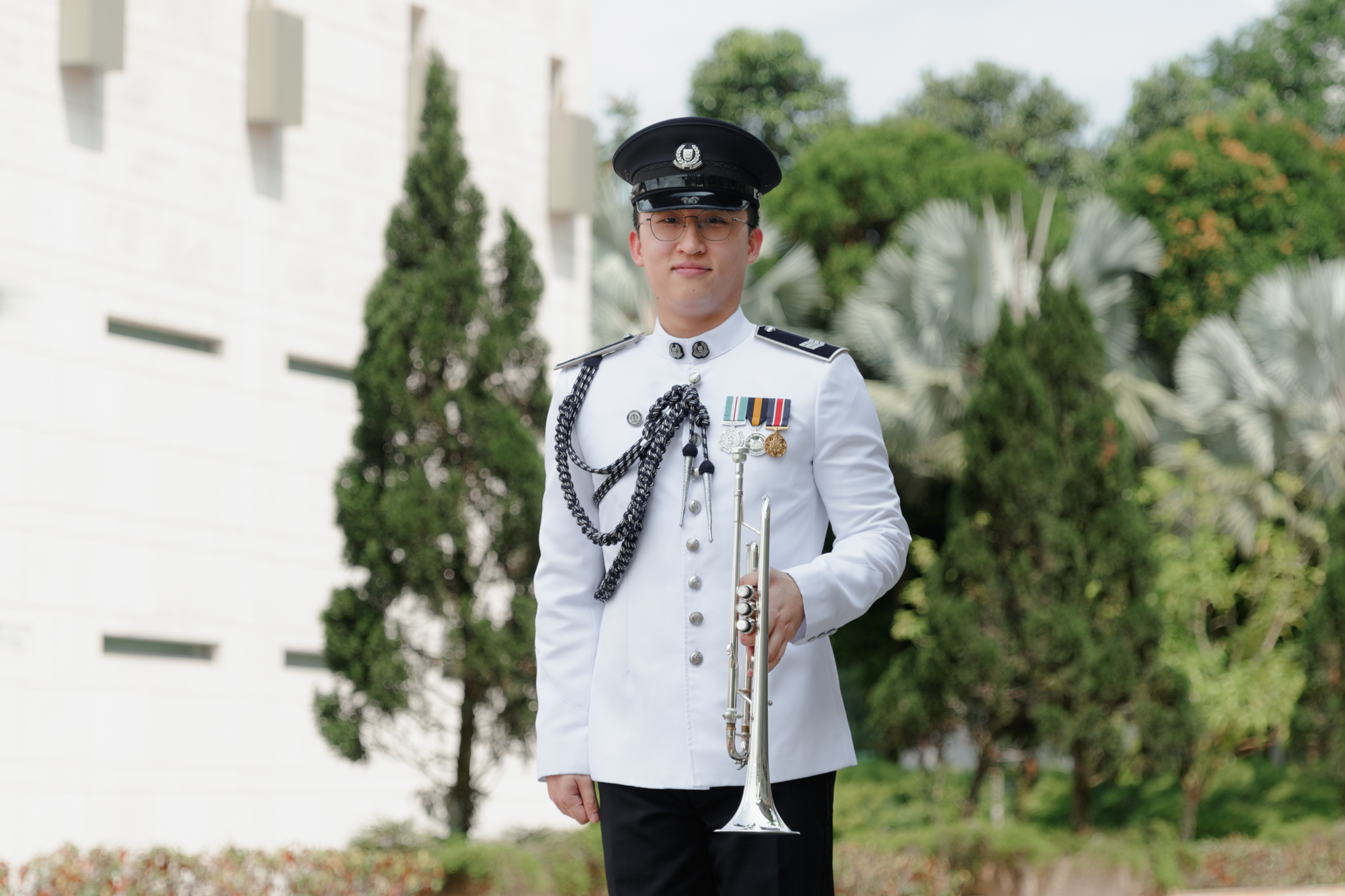 a photo of a band officer in ceremonial attire standing, holding his trumpet on the left hand