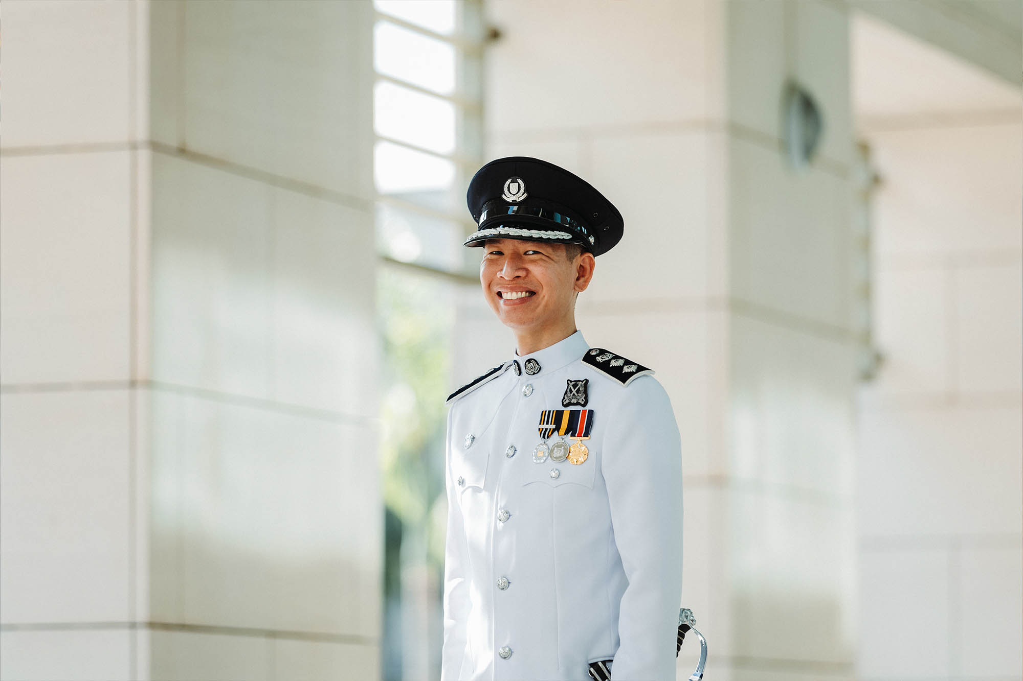 a photo of supt (ns) cyril in no.1 standing along a hallway and smiling at the camera
