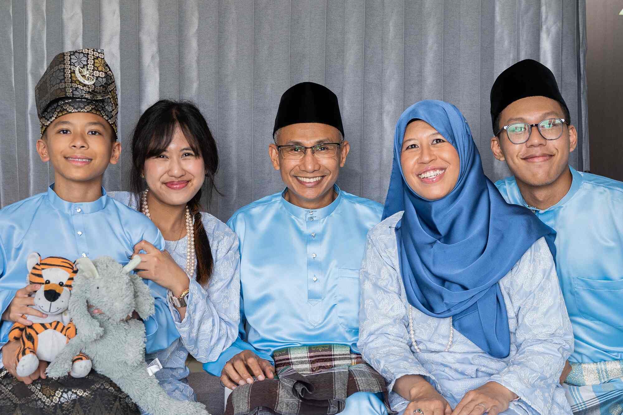 a photo of AC Masagoes and in family, dressed in a light blue traditional malay outfit for Hari Raya