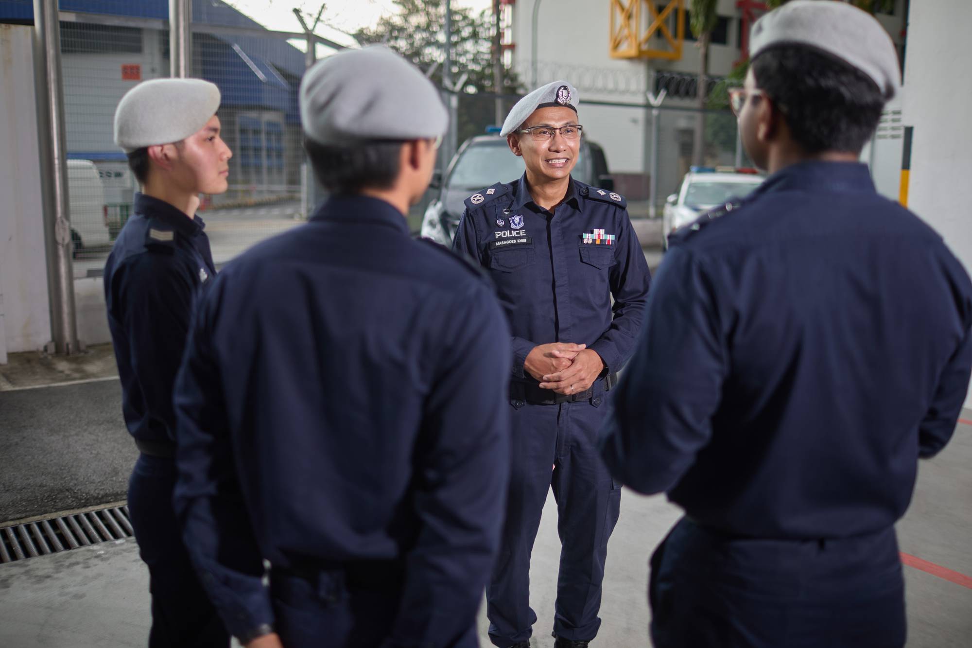 commander masagoes standing in the middle of transcom officers surrounding him. All are wearing their uniforms and their grey berets